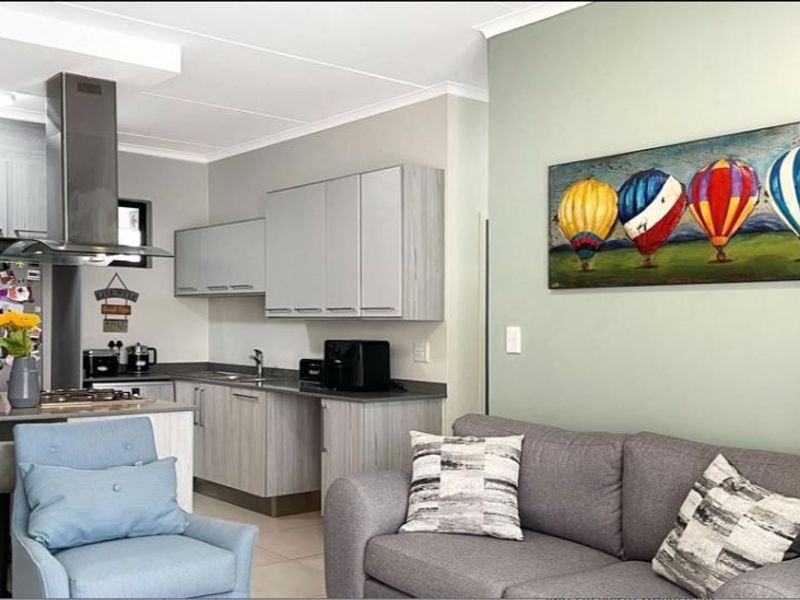 Modern open-plan living area featuring a contemporary kitchen with sleek cabinetry, stainless steel extractor fan, and integrated sink, seamlessly flowing into the lounge space.