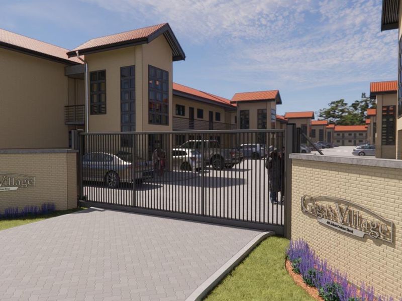 Front entrance view of Giga's Village apartment complex, featuring a secure gated access point, paved driveway, and modern multi-story residential buildings.