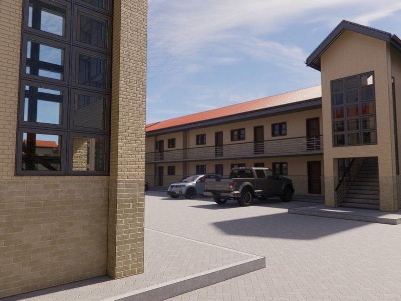 Exterior view of a modern apartment complex featuring brick facade, paved parking area, and external staircases leading to upper-level units.