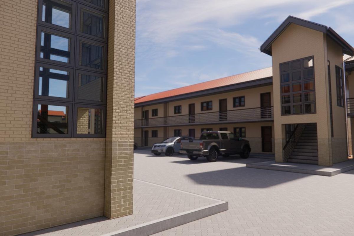 Exterior view of a modern apartment complex featuring brick facade, paved parking area, and external staircases leading to upper-level units.