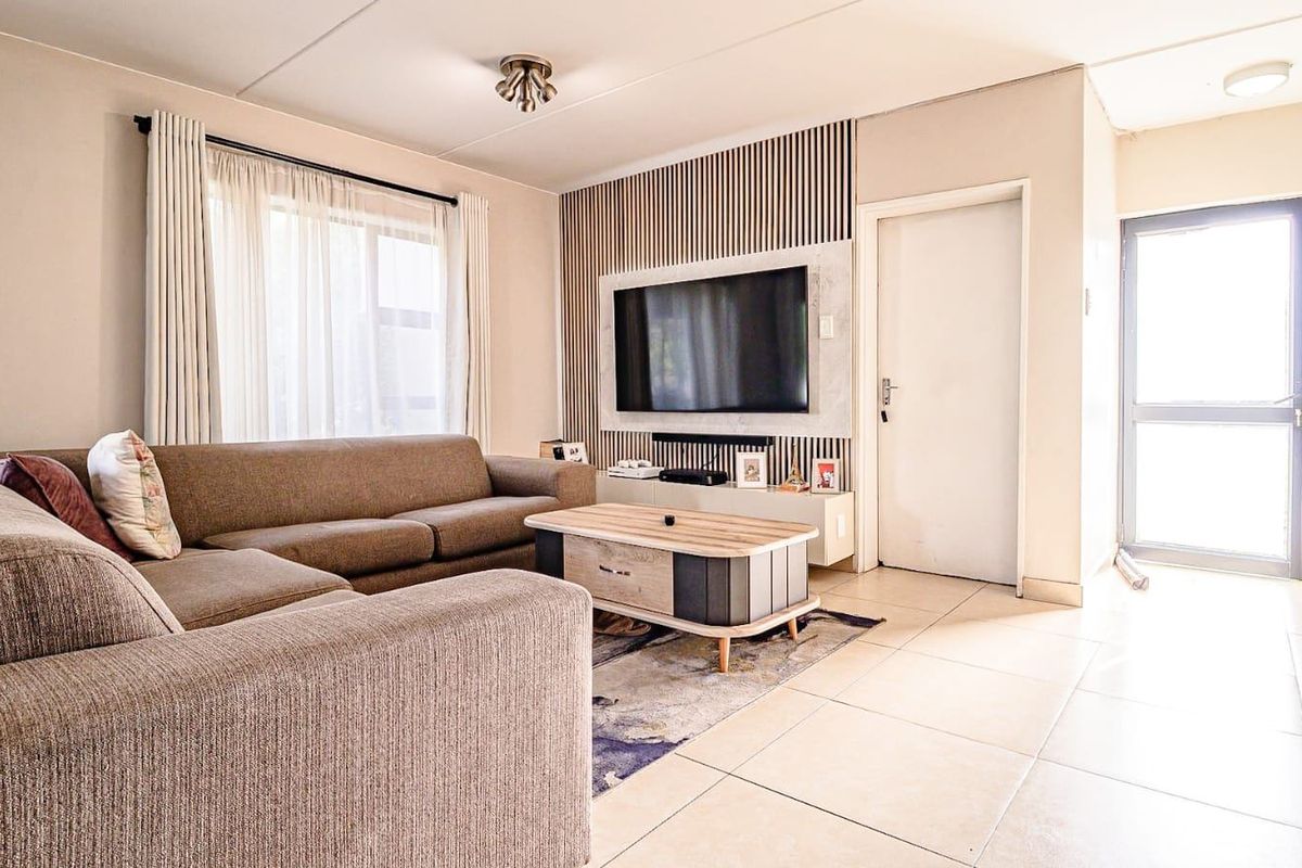 A well-lit living room featuring tiled flooring, a decorative feature wall, and direct access to an exterior door.