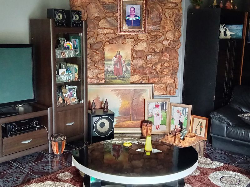 A living room featuring a prominent natural stone feature wall and dark tiled flooring, creating a cozy and traditional atmosphere.