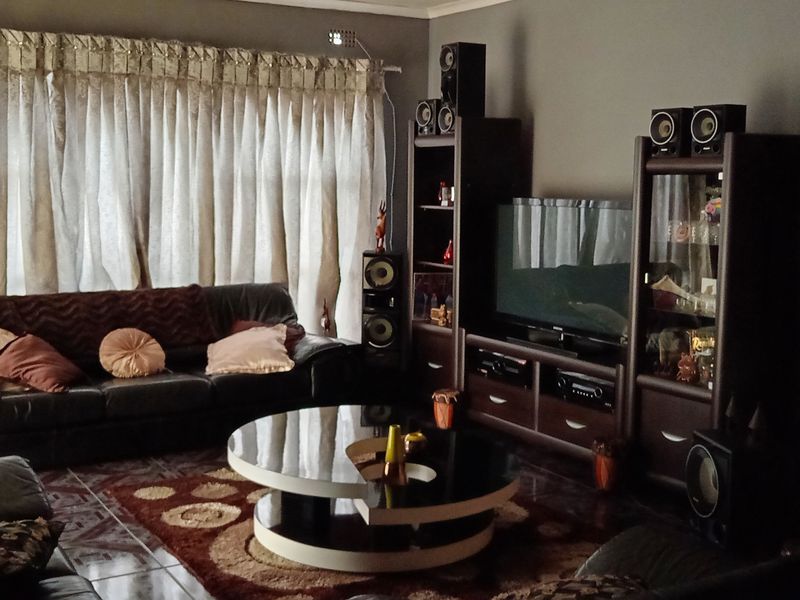A comfortable living room featuring tiled flooring and large window treatments, providing a functional space for relaxation and entertainment.