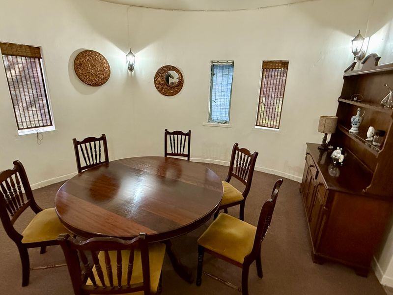 A circular dining room featuring curved walls, multiple windows, and wall-mounted light fixtures.
