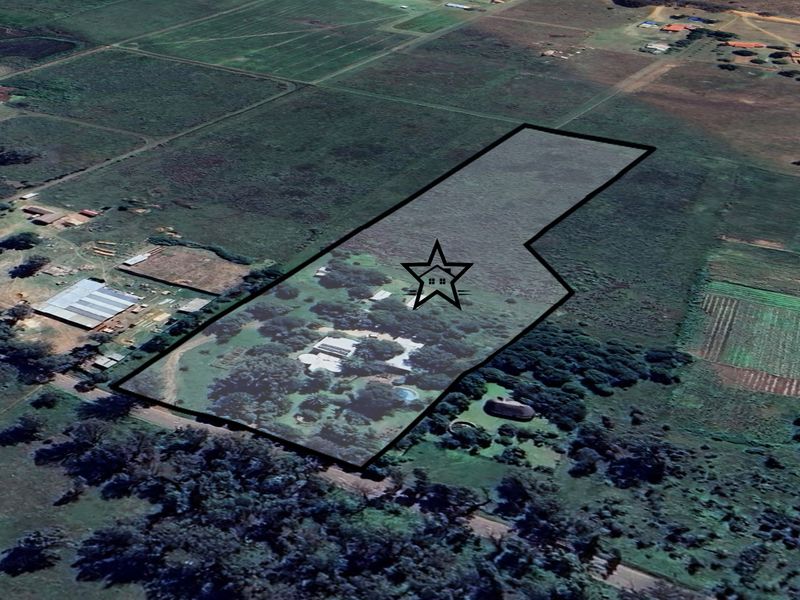 Aerial view of a large rural property plot with established trees, a main dwelling, and surrounding agricultural land.