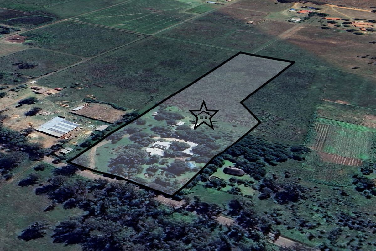 Aerial view of a large rural property plot with established trees, a main dwelling, and surrounding agricultural land.