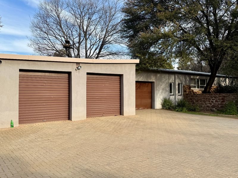 A view of the property's exterior featuring a triple garage with roller doors and a paved driveway area.