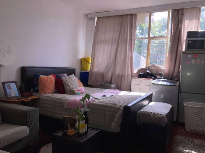 A bedroom featuring a large window with security bars, providing natural light and a view of the exterior surroundings.