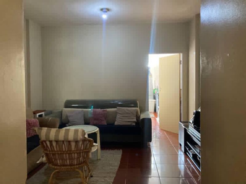 A living room area featuring tiled flooring and neutral wall finishes, providing a functional space with access to an adjacent room.