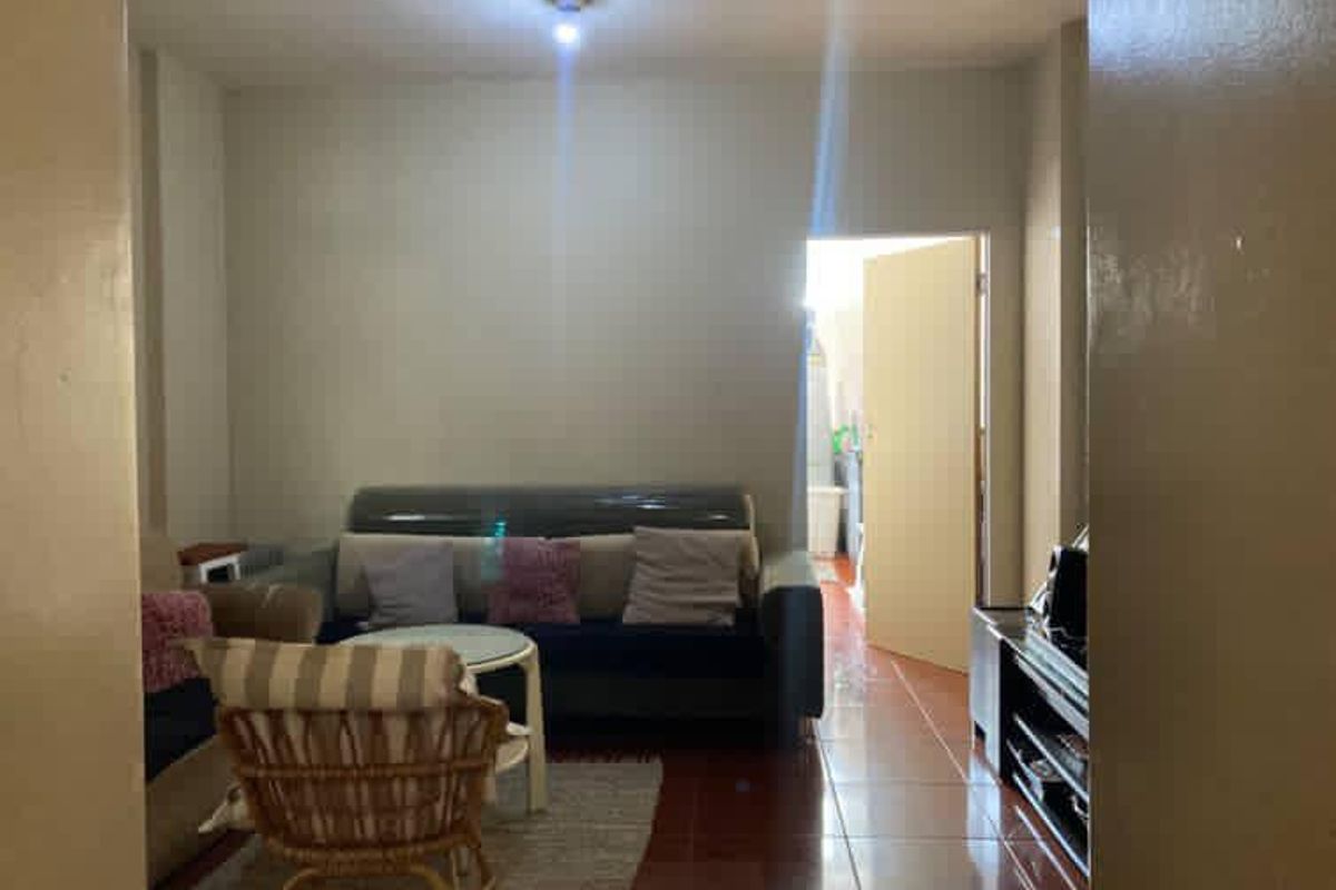 A living room area featuring tiled flooring and neutral wall finishes, providing a functional space with access to an adjacent room.