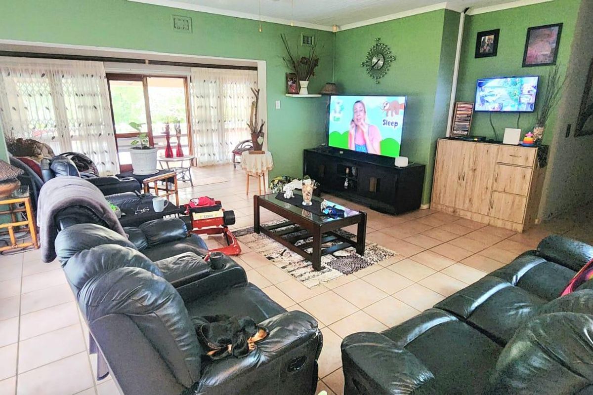 Spacious living room featuring tiled flooring, a ceiling fan, and large sliding glass doors providing access to the outdoor area.
