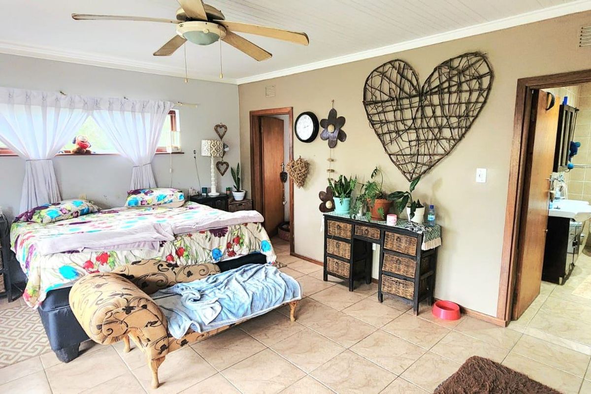 Spacious bedroom featuring tiled flooring, a ceiling fan, and an attached en-suite bathroom with neutral finishes.