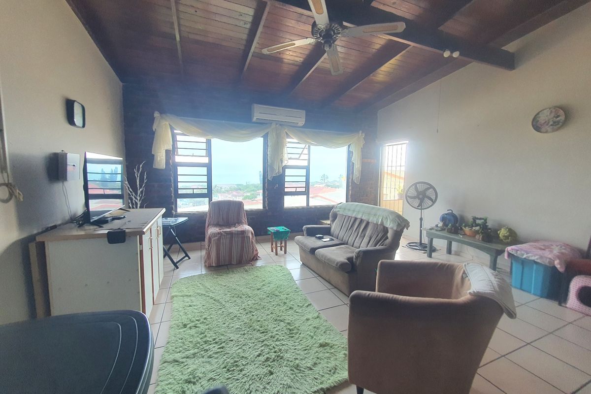 Spacious living room featuring a high exposed timber beam ceiling, brick feature wall, tiled flooring, and a split-system air conditioner.