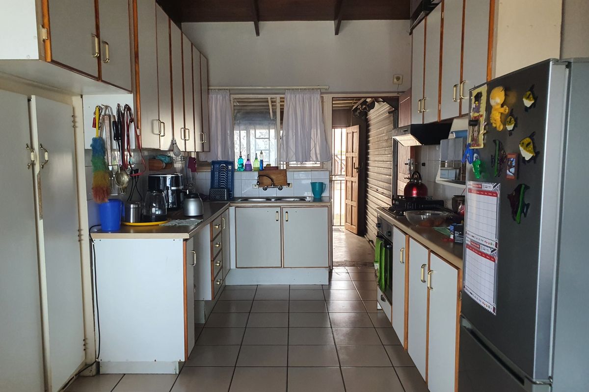 A functional galley-style kitchen featuring laminate cabinetry, tiled flooring, and a built-in oven, offering a dated aesthetic ready for modern renovation.