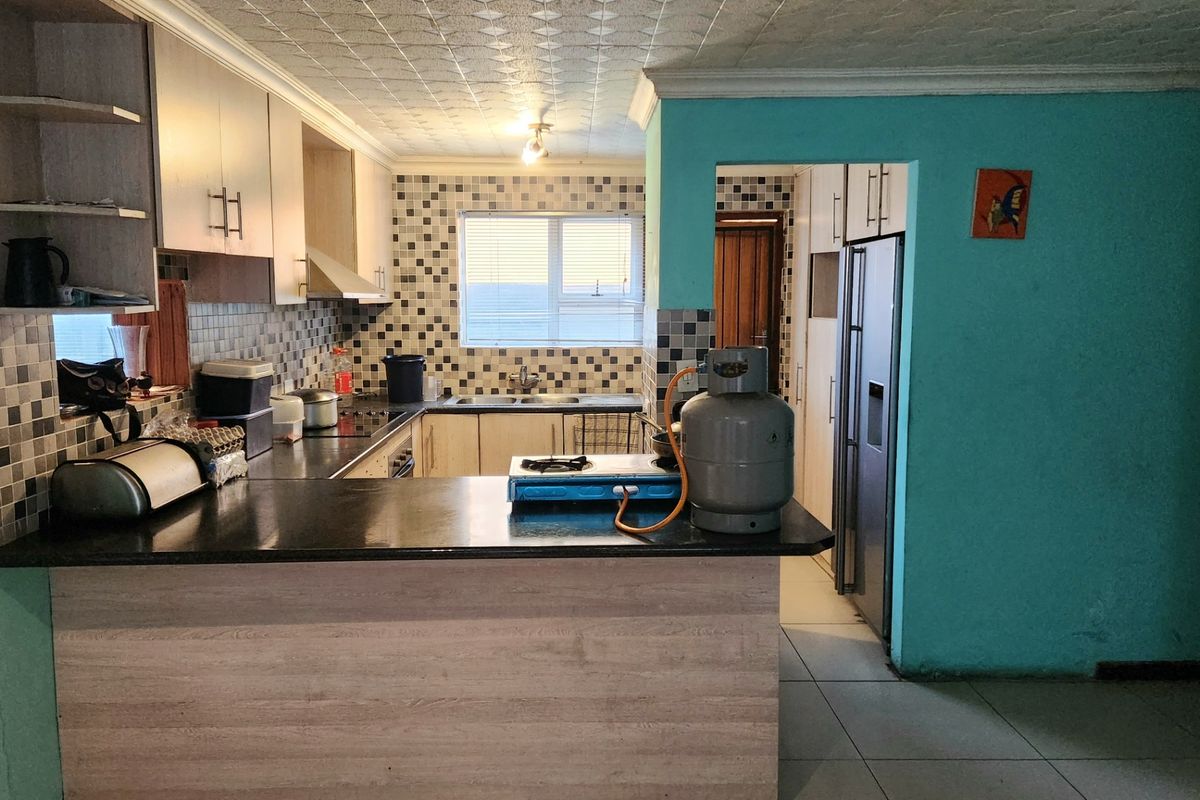 Functional kitchen featuring built-in cabinetry, tiled backsplash, and a breakfast bar, offering a practical layout with potential for modern updates.