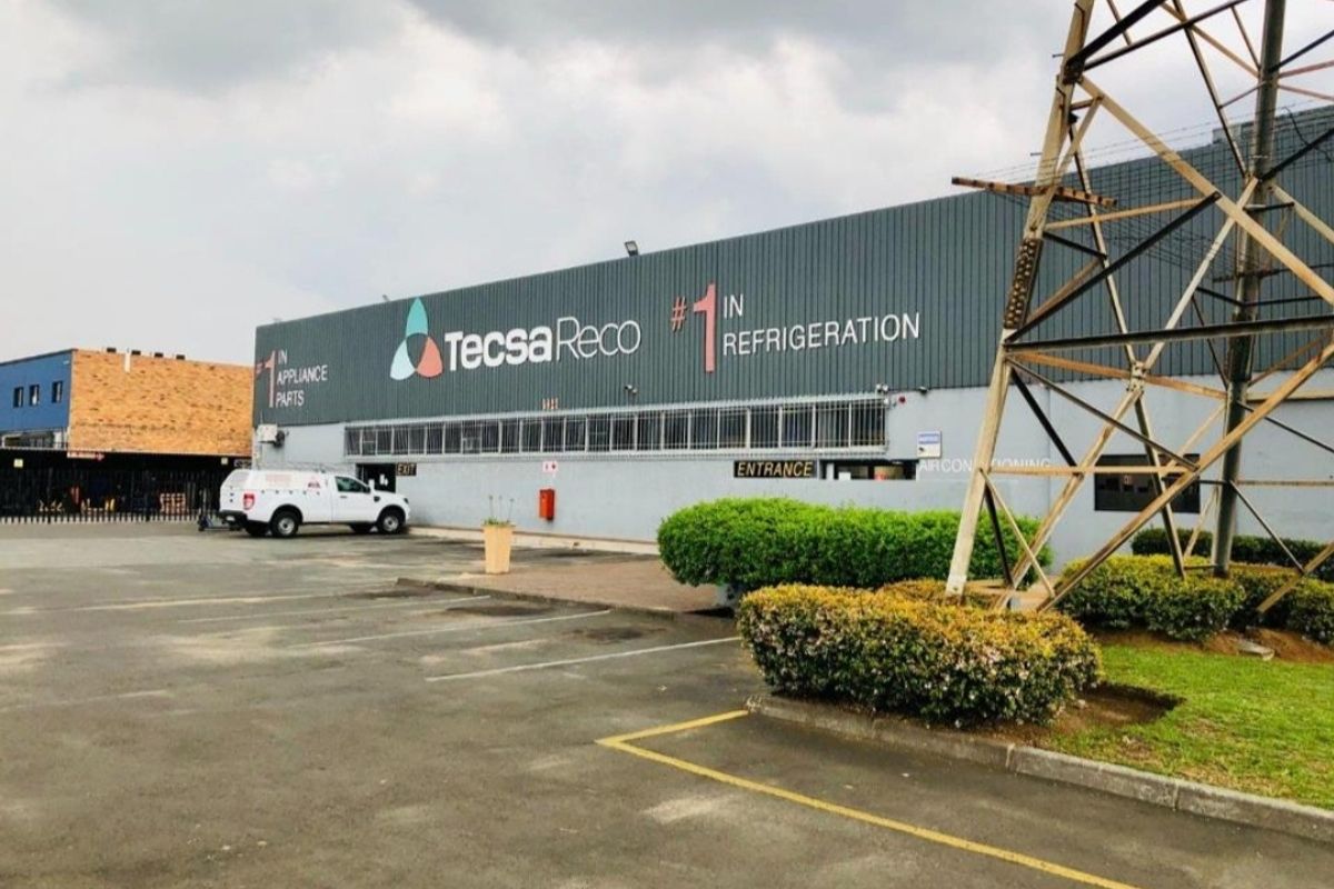 Front elevation of an industrial warehouse facility featuring metal cladding, dedicated parking area, and prominent signage.