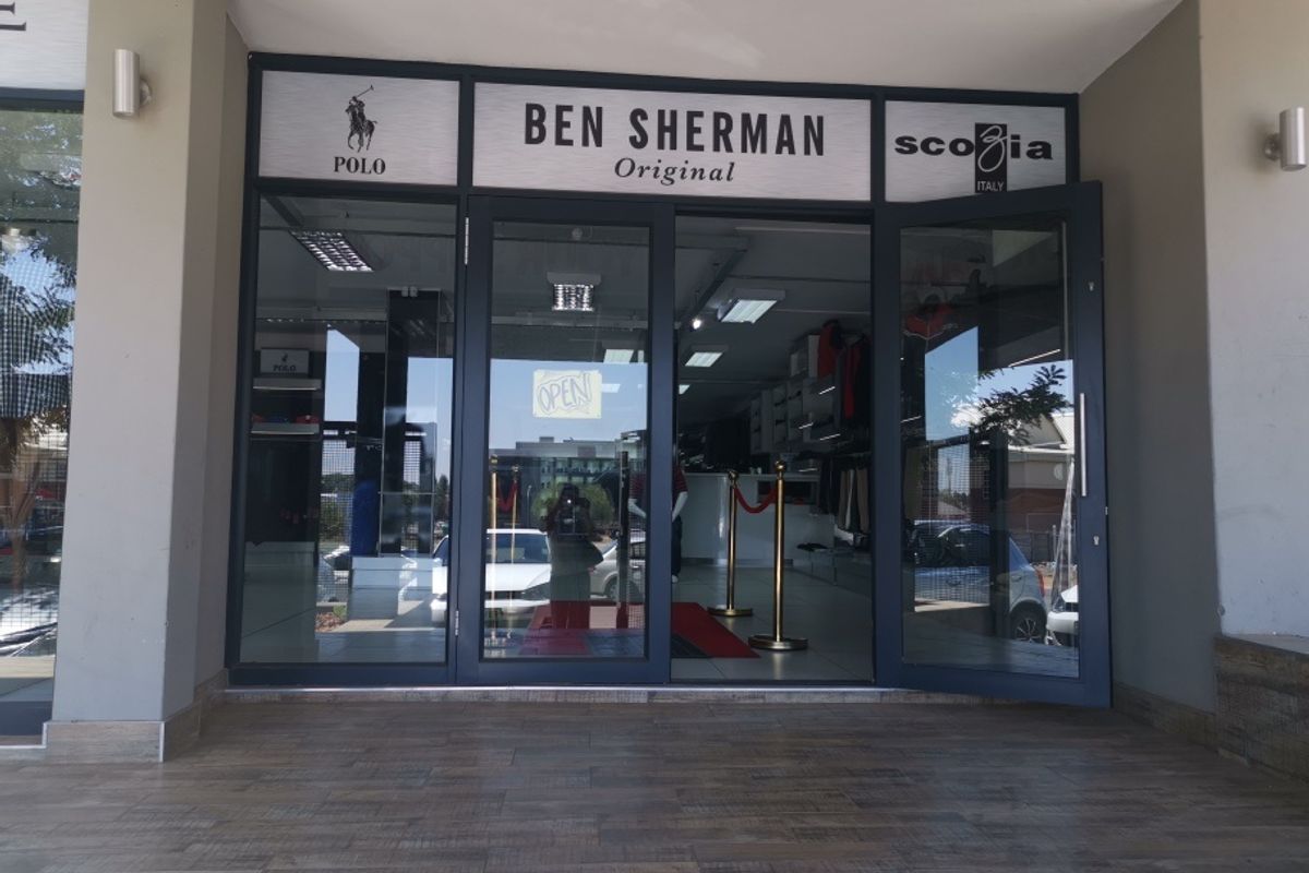 Commercial storefront entrance featuring modern glass doors, aluminium framing, and tiled flooring, providing clear visibility into the retail space.