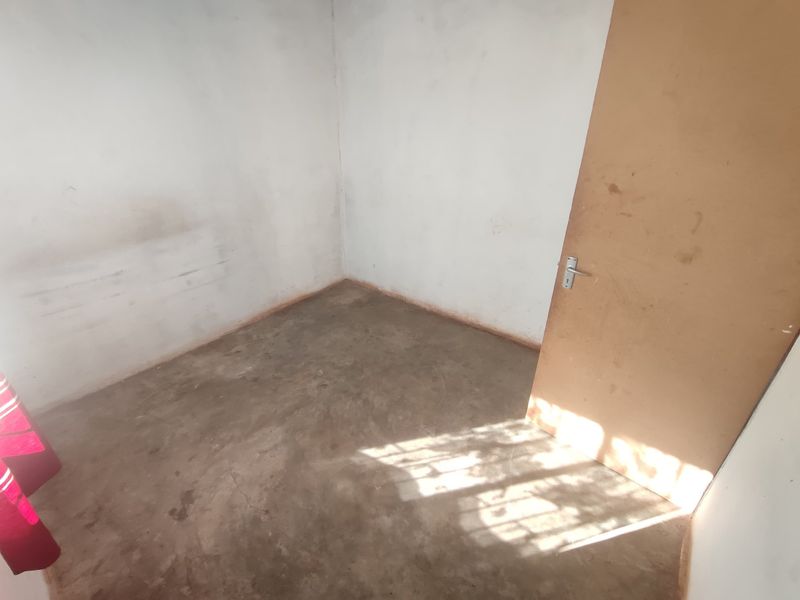 An empty, unfinished bedroom featuring bare concrete flooring and plain walls, presenting a blank canvas for renovation and interior design.