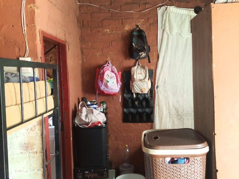 A small bedroom featuring exposed brick walls and a corrugated iron roof, requiring significant maintenance and finishing to improve the living space.