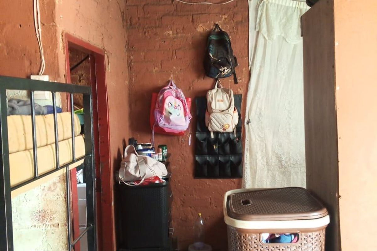 A small bedroom featuring exposed brick walls and a corrugated iron roof, requiring significant maintenance and finishing to improve the living space.