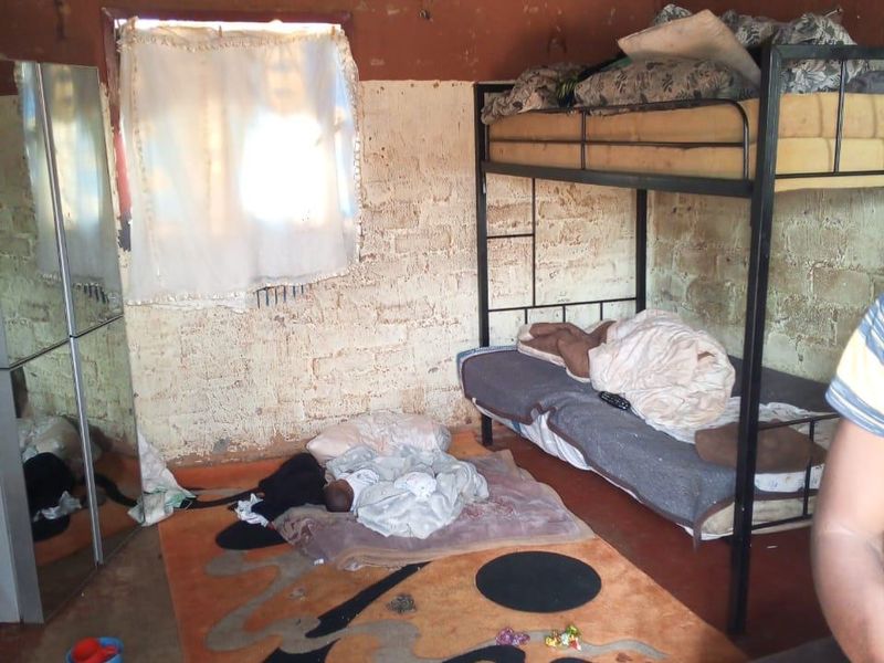 A basic bedroom featuring exposed brick walls, a corrugated metal roof, and a concrete floor, requiring significant renovation to improve finishes.