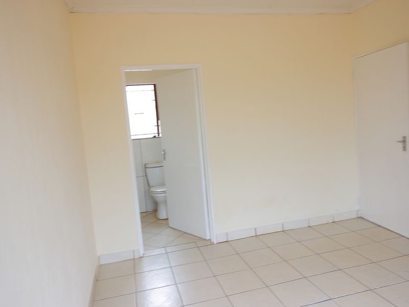 An empty bedroom featuring tiled flooring and direct access to an en-suite bathroom, providing a blank canvas for personalization.