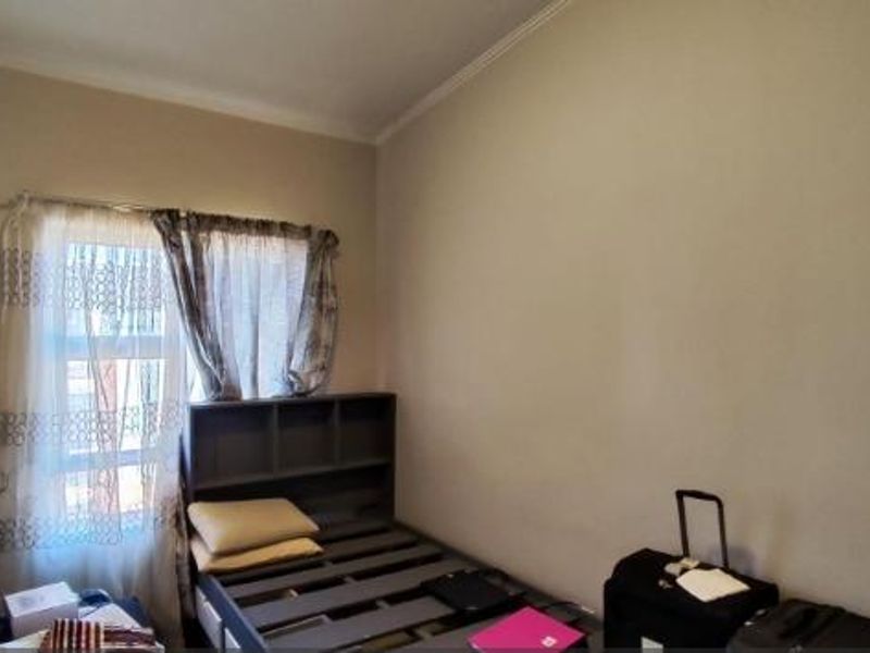 A standard bedroom featuring a window with curtains and neutral wall finishes.