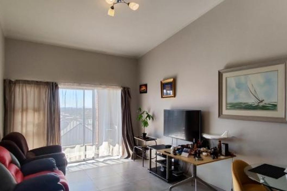 A living room featuring tiled flooring and a large sliding glass door that provides natural light and access to the exterior.