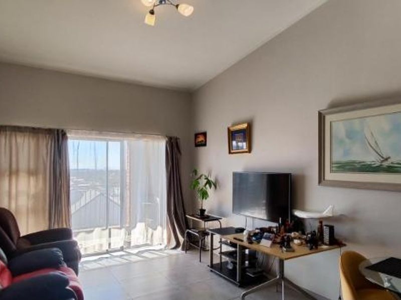 A living room featuring tiled flooring and a large sliding glass door that provides natural light and access to the exterior.