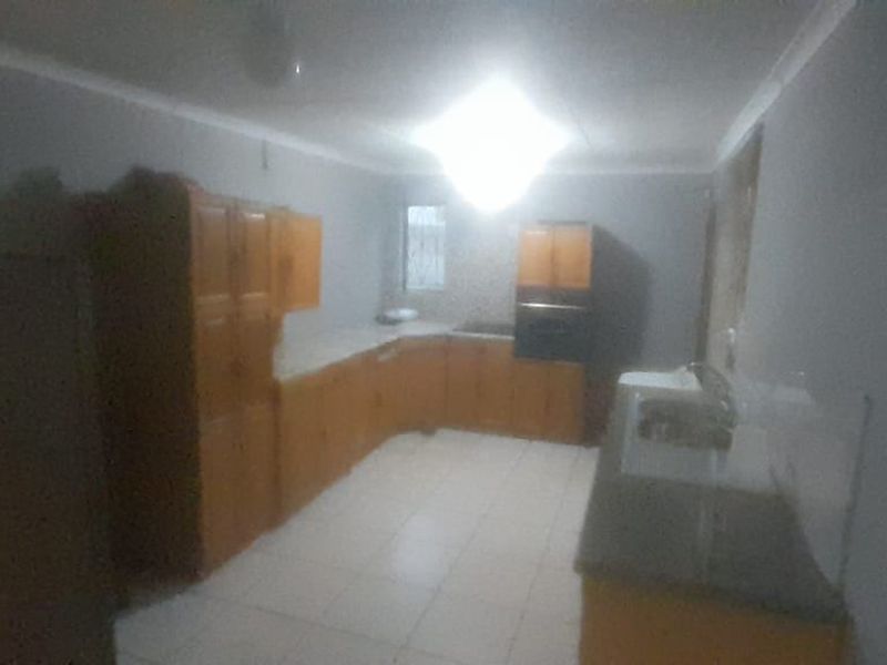 A functional kitchen featuring built-in wooden cabinetry, a built-in oven, and tiled flooring, offering a practical layout for daily meal preparation.