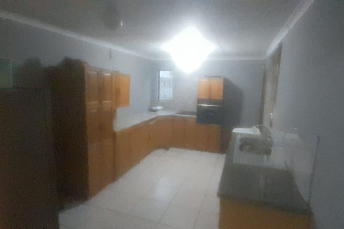 A functional kitchen featuring built-in wooden cabinetry, a built-in oven, and tiled flooring, offering a practical layout for daily meal preparation.