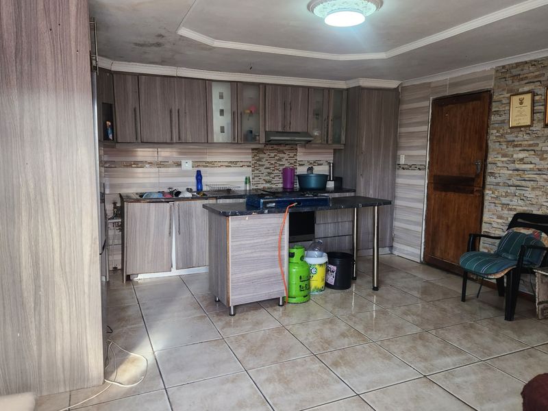 Kitchen featuring laminate cabinetry, stone-look tile flooring, and a stone veneer feature wall. The ceiling shows visible signs of water damage.