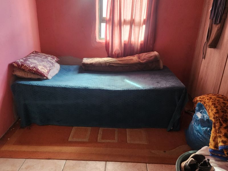 A compact bedroom featuring tiled flooring and a built-in wardrobe, requiring cosmetic updates to the wall finishes and general maintenance.