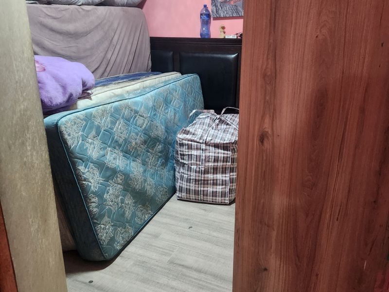 A small bedroom featuring laminate flooring and pink wall finishes, currently used for storage.