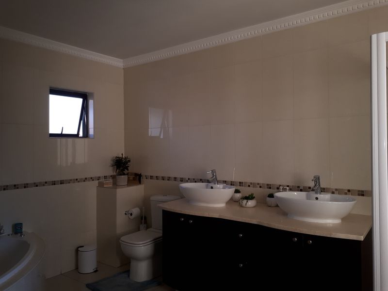 A well-maintained bathroom featuring a double vanity with vessel sinks, tiled walls, and crown molding.