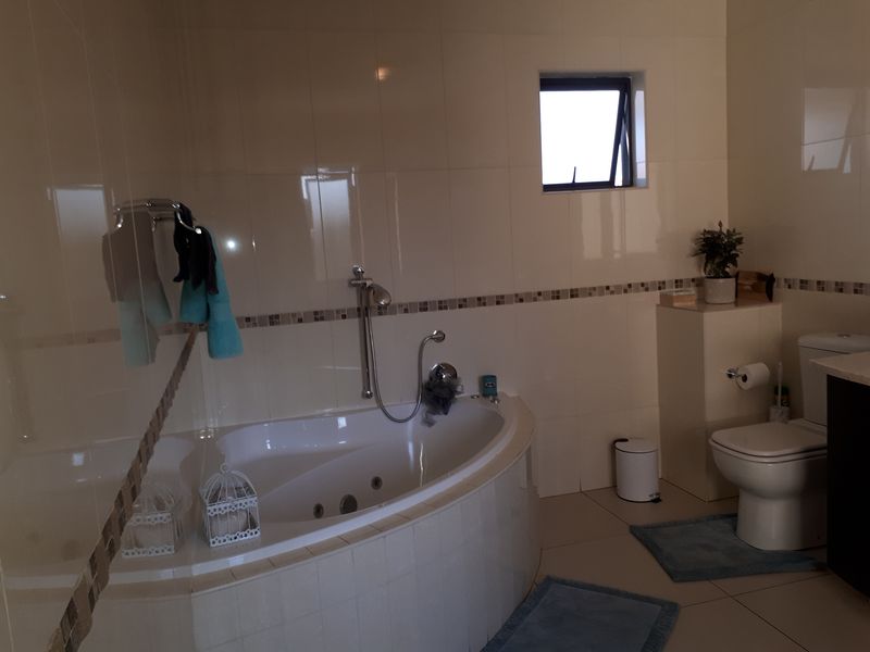 A functional bathroom featuring a corner bathtub, tiled wall finishes, and a standard toilet, providing a practical layout with natural light from a small window.