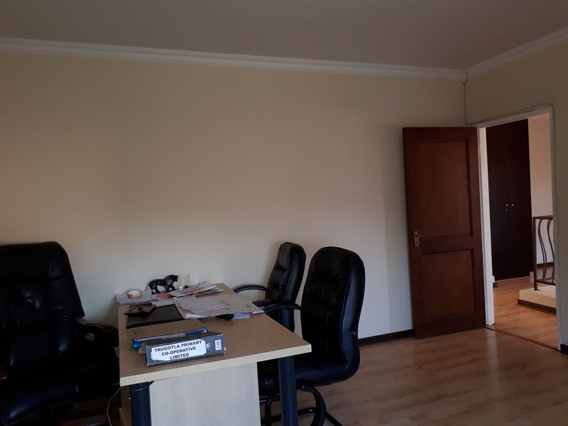A functional office space featuring laminate flooring, crown molding, and a solid wood door, providing a quiet area for work or study.