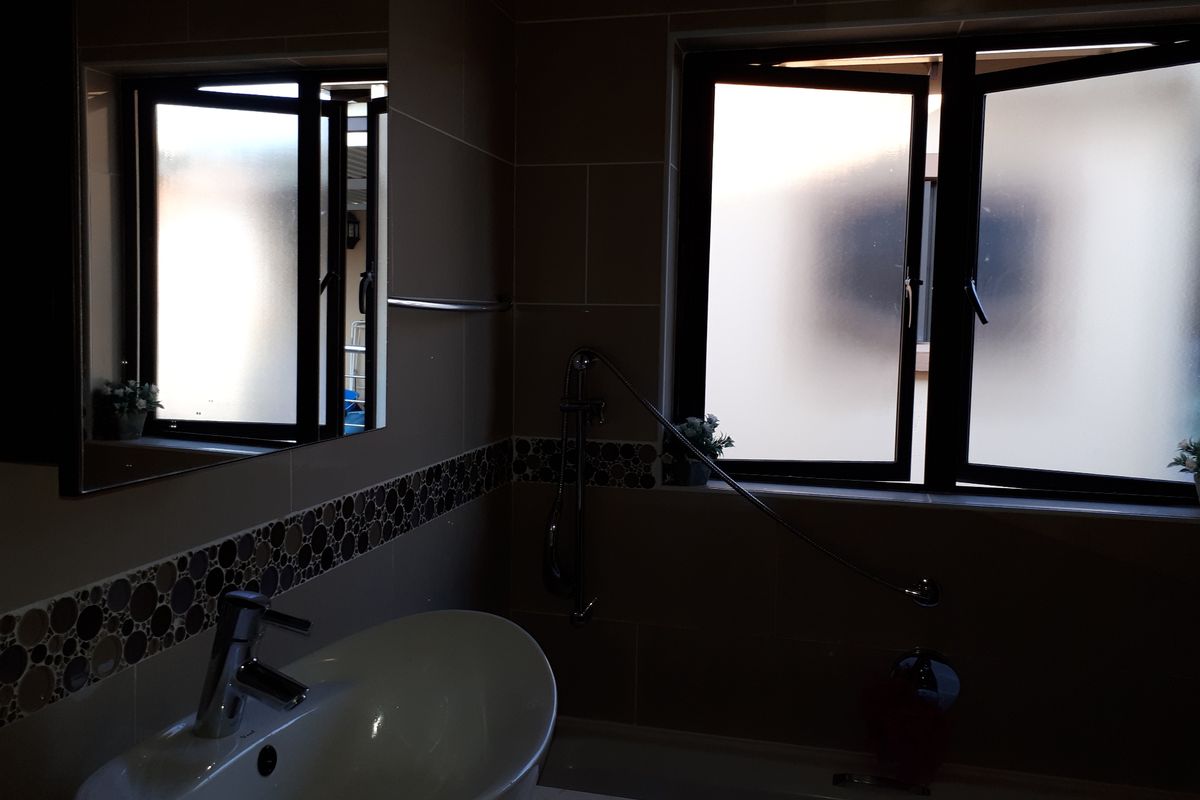 A functional bathroom featuring a basin, bathtub with shower attachment, and tiled walls with decorative mosaic accents.