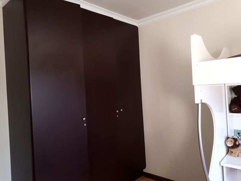 A bedroom featuring dark built-in cupboards and decorative ceiling cornicing.
