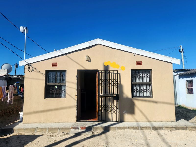 Front elevation of a single-story house featuring a security gate, security bars on windows, and a concrete apron.