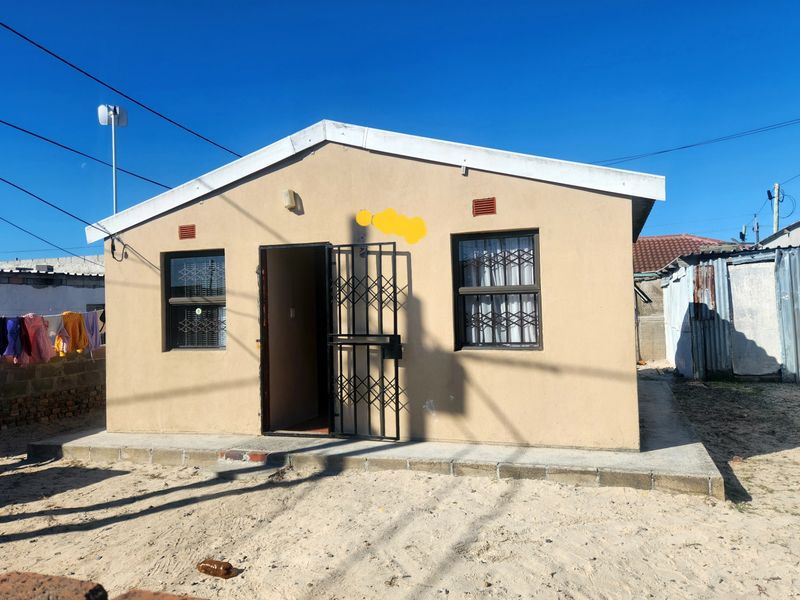 Front elevation of a single-story house featuring a security gate, burglar bars, and a concrete apron entrance.