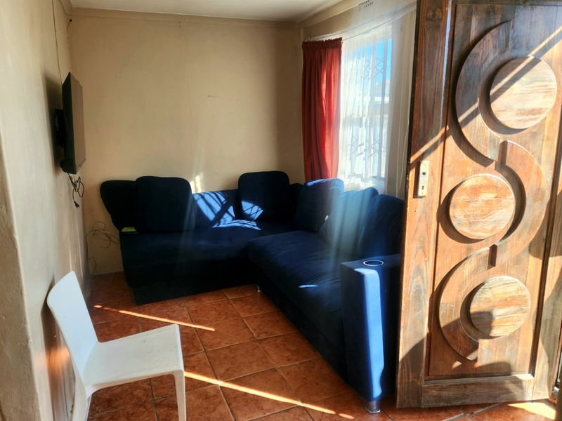 A compact living area featuring tiled flooring and a decorative timber door, requiring cosmetic updates to improve the overall aesthetic.