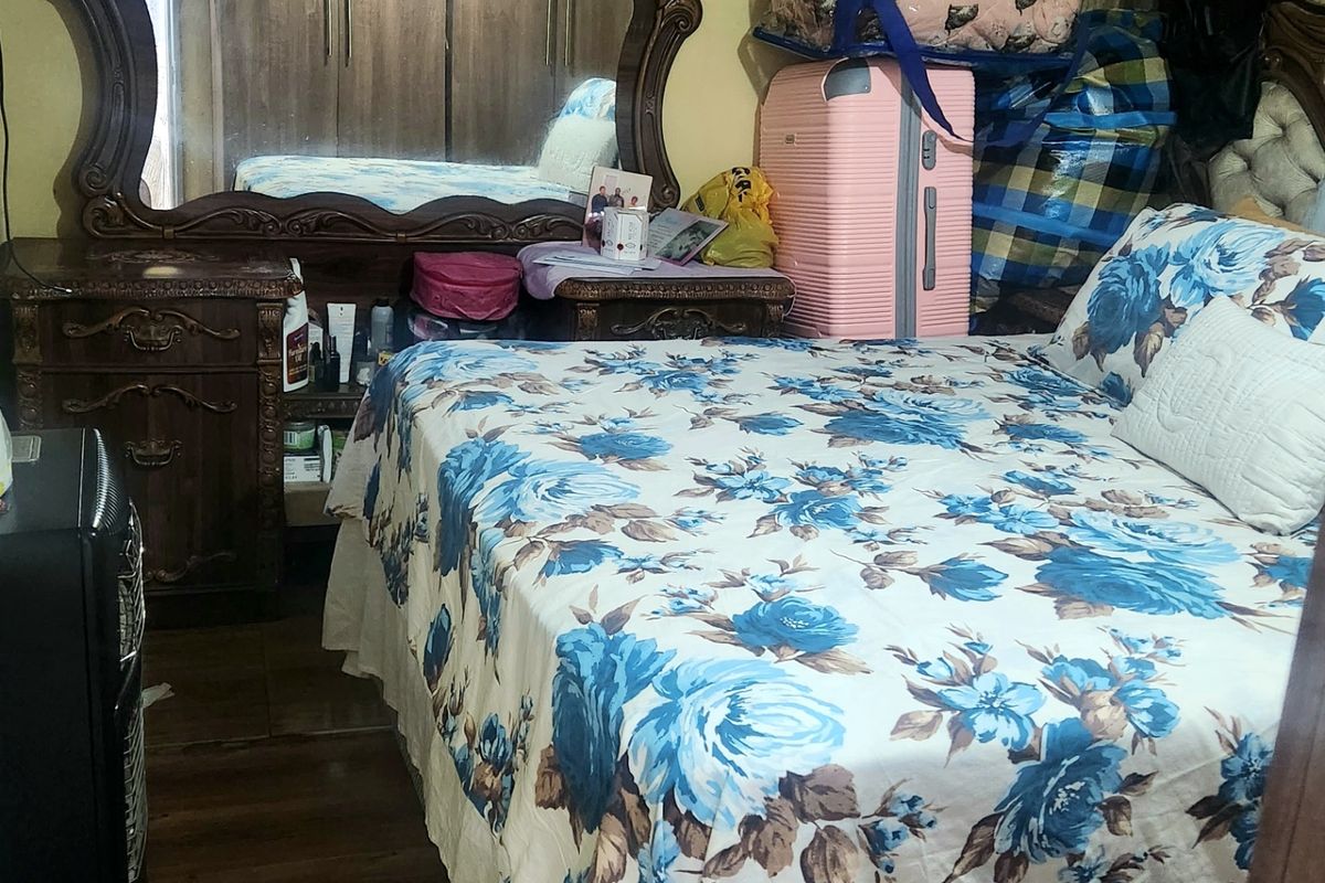 A bedroom featuring laminate flooring and a built-in wardrobe, currently showing signs of wear on the walls.
