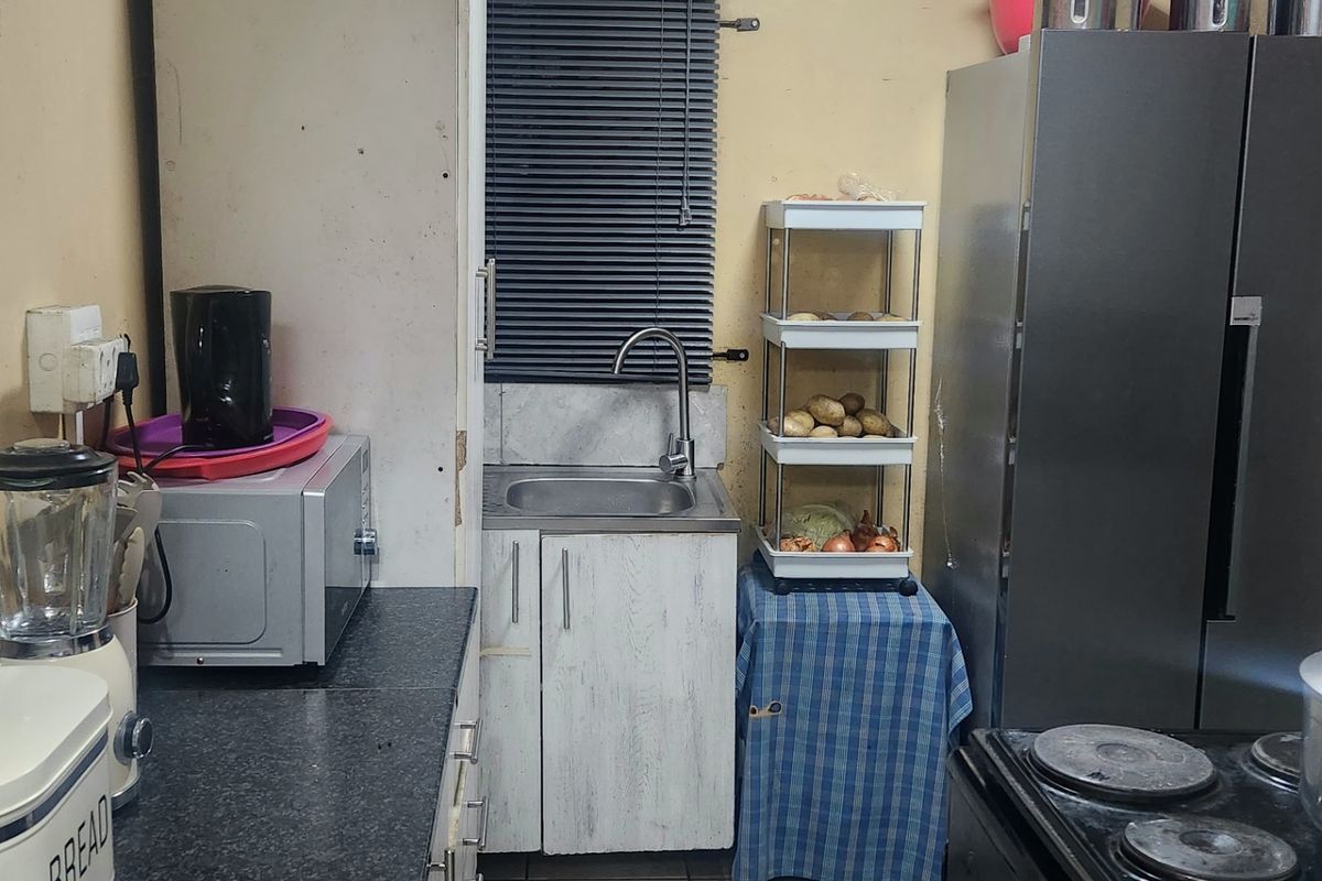 A compact kitchen featuring laminate countertops, base cabinetry, and tiled flooring. The space requires cosmetic updates to improve its overall condition and aesthetic appeal.