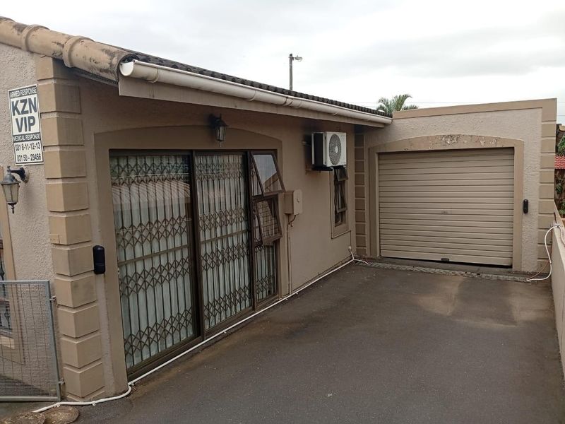 Front exterior view of the house featuring a roller garage door, sliding glass entrance with security gate, and an installed air conditioning unit.
