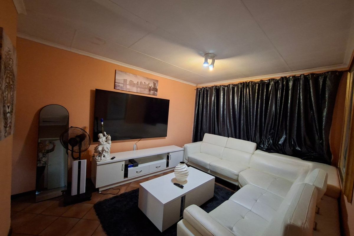 A living room featuring tiled flooring and a ceiling-mounted spotlight, providing a functional space for relaxation.
