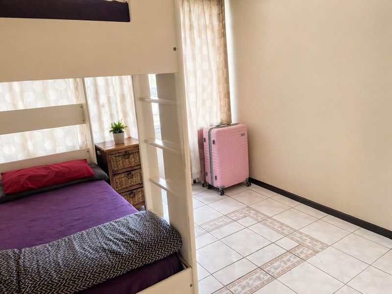 A bedroom featuring tiled flooring and a window with curtains, providing a functional space for rest.