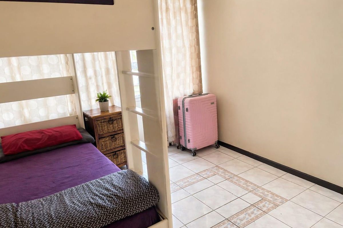 A bedroom featuring tiled flooring and a window with curtains, providing a functional space for rest.