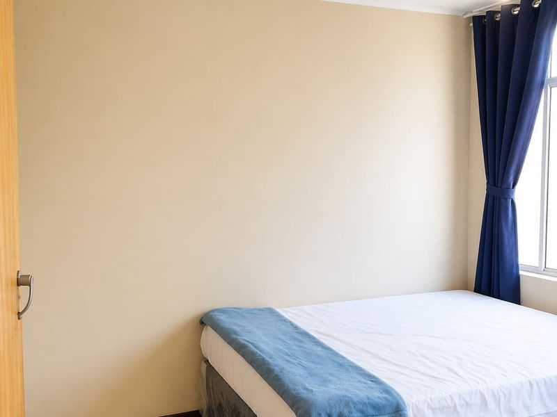 A bedroom featuring tiled flooring and a ceiling fan, providing a functional and neutral space.