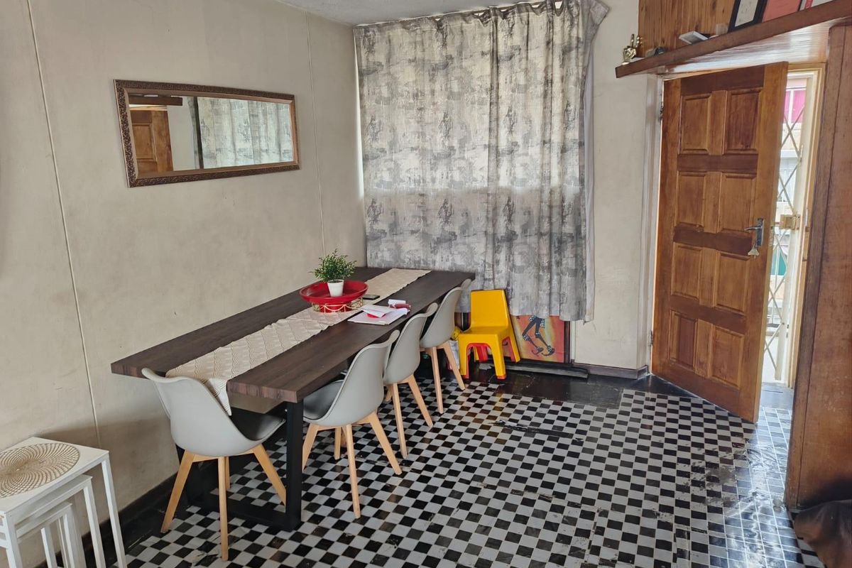 Dining area featuring a distinctive checkered tile floor, timber door, and wood paneling accents, offering a functional space with potential for cosmetic updates.
